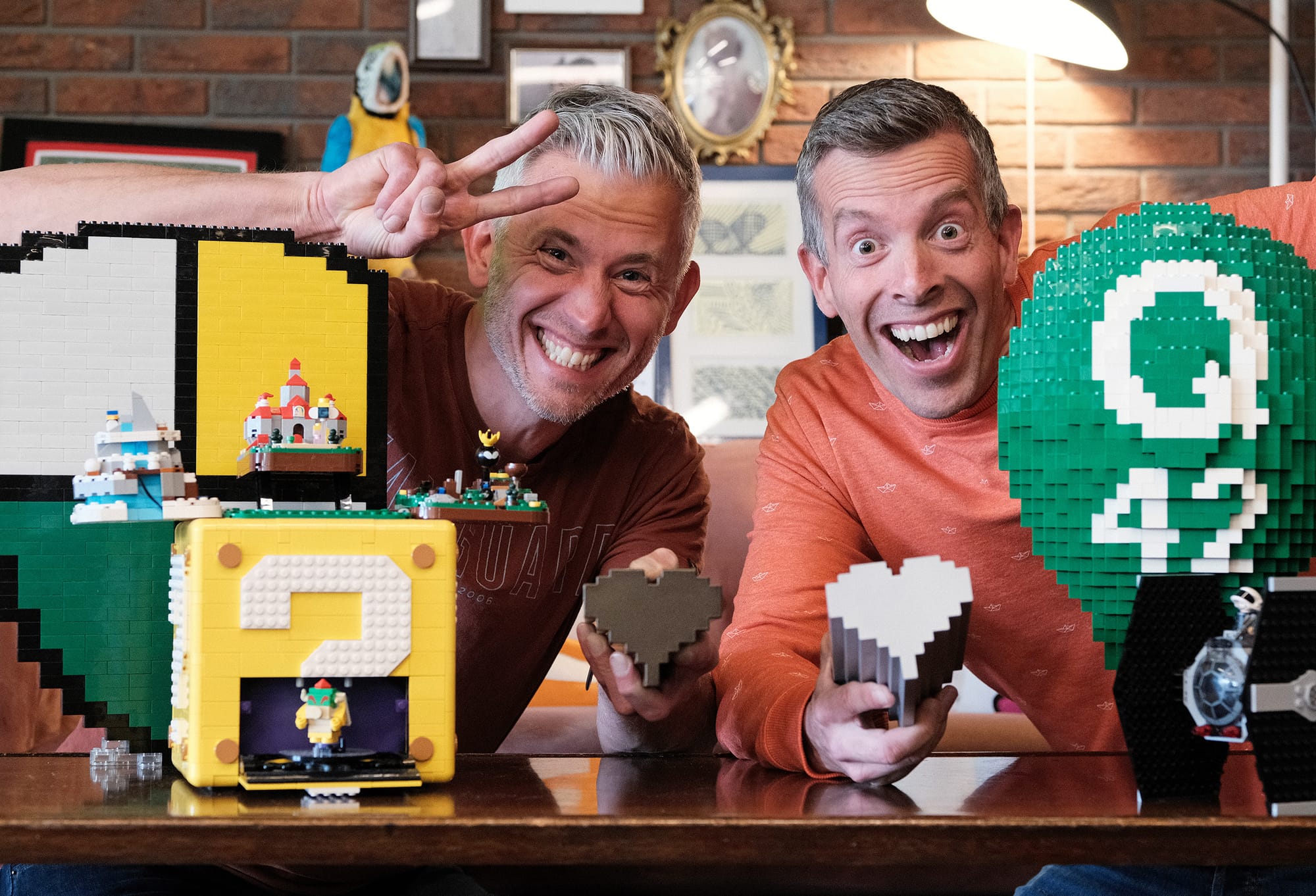Twee blij uitziende, grijzende mannen met LEGO om zich heen en awards in hun handen.