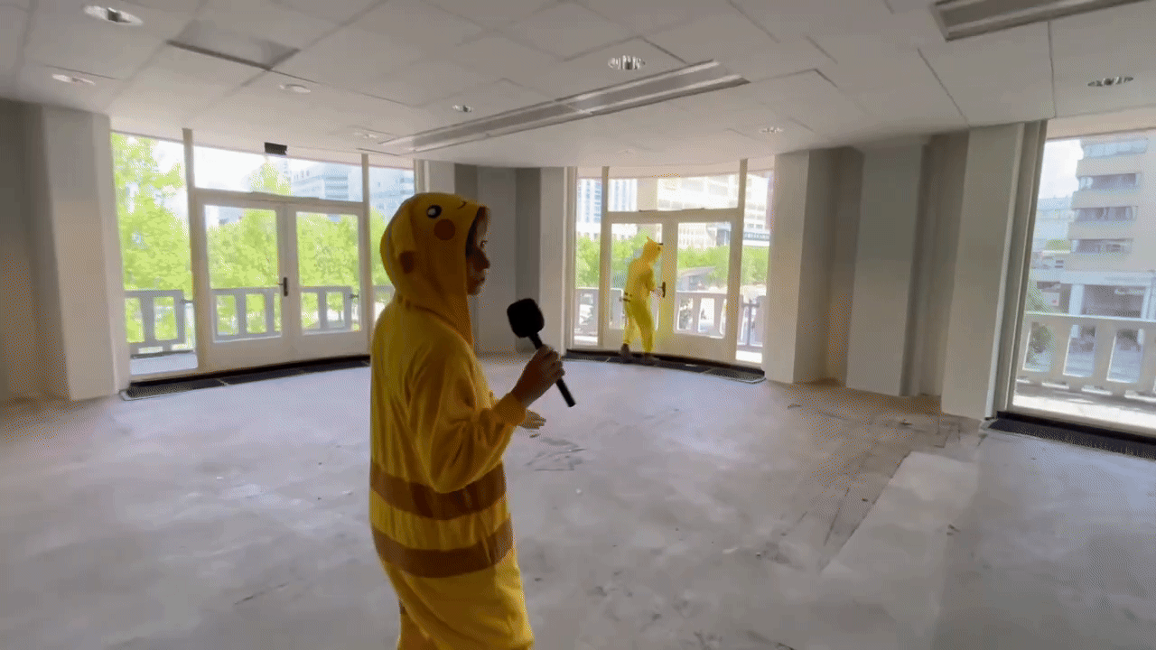 Gifje van twee als Pikachu verklede mensen in een lege kantoorruimte.