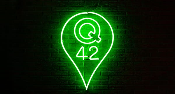 Foto van het Q42-logo als neonversie gemonteerd aan een bakstenen muur.